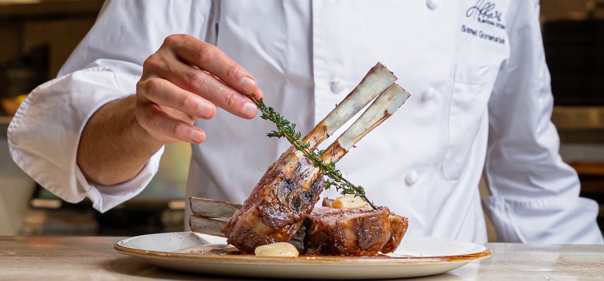 Abbale chef presenting a bone-in Mediterranean meat dish with precision